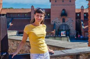 jovem viajante olhando para a câmera, posando e sorrindo no pátio do antigo castelo da ilha medieval de trakai