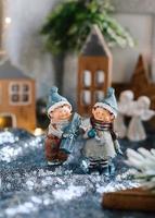 estatuetas de porcelana de crianças em uma decoração de natal. figuras de inverno de um menino e uma menina com presentes no fundo de casas e cones. cartão de natal. copie o espaço. foto