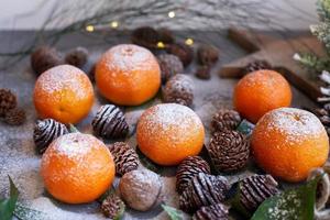 tangerinas laranja em fundo cinza na decoração de ano novo com pinhas marrons e folhas verdes. decoração de natal com tangerinas. deliciosa clementina doce. foto