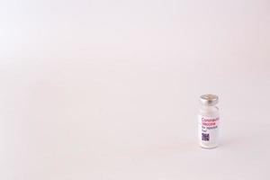 vacina para o coronavírus. preparação médica em ampola. tratamento para a doença, covid-19. a vacina em um fundo branco e no fundo de uma seringa, luvas de borracha e óculos de proteção foto