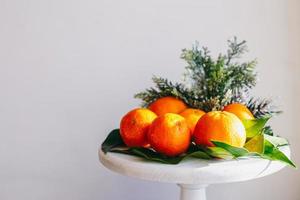 tangerinas laranja em fundo cinza na decoração de ano novo com pinhas marrons e folhas verdes. decoração de natal com tangerinas. deliciosa clementina doce. foto