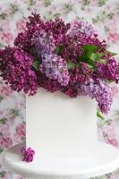 lençol branco em lindo lilás florescendo em um carrinho branco sobre um fundo floral. cartão de felicitações, lugar para texto, mock up