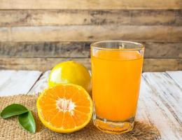 copo de suco de laranja recém-prensado com laranja fatiada na mesa de madeira