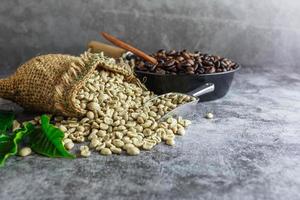 grãos de café não torrados verdes crus em sacos marrons e grãos de café torrados em uma panela. foto