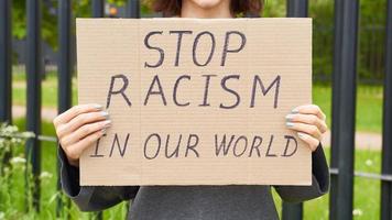pare o conceito de racismo. pessoa branca irreconhecível segura placa com texto contra racista. foto