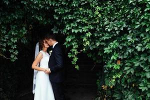 lindo jovem casal de noivos beijando, noiva loira com flowe foto