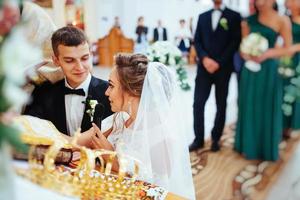 noivo colocando aliança no dedo da noiva durante o casamento foto
