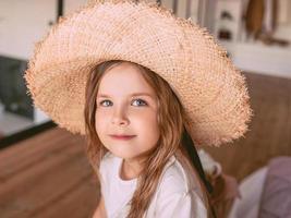 adorável menina alegre com chapéu de palha em casa interior. moda, estilo, infância, emoções, conceito de crescimento foto