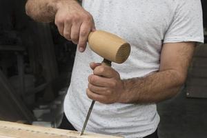 o carpinteiro em uma camiseta branca funciona como um cinzel e um martelo foto