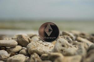 criptomoeda ethereum. moeda eletrônica. praia de verão. pedras do mar foto