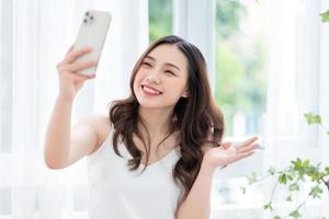 jovem mulher asiática usando smartphone em casa pela manhã foto