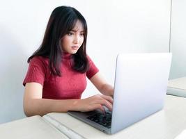 menina bonita asiática séria ou pensando na frente do laptop no fundo branco isolado foto