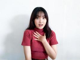 uau e rosto chocado da bela jovem asiática com a mão tocando o peito usar camisa vermelha. conceito de modelo de publicidade. foto