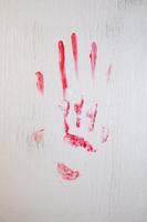 marca de mão sangrenta manchada de sangue na janela de vidro fosco foto