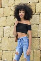 jovem mulher mista com cabelo afro em pé na rua foto