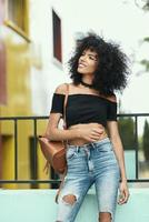 mulher mista sorridente com cabelo afro em pé na rua foto