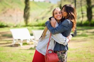 jovem mulher beijando o rosto do amigo ao ar livre foto