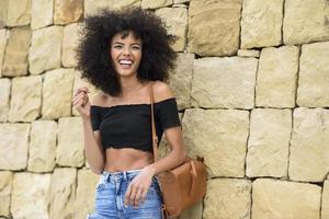 feliz mulher mista com cabelo afro rindo ao ar livre foto