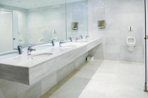 banheiro público masculino vazio com espelho de lavatórios foto