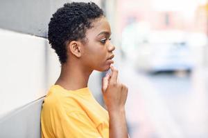mulher negra pensativa com expressão triste ao ar livre.