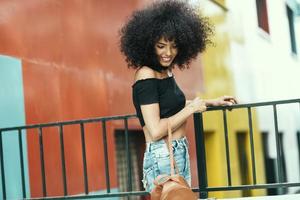 jovem mulher com cabelo encaracolado perto de um edifício moderno e colorido foto