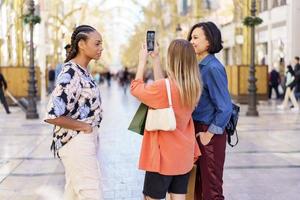 diversas mulheres tomando selfie em smartphone na rua foto