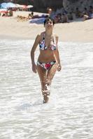 mulher com corpo bonito em trajes de banho sorrindo em uma praia tropical. foto