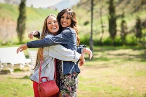 dois amigos de mulheres jovens felizes abraçando no parque urbano. foto