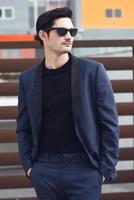 homem, modelo de moda, vestindo terno moderno e óculos de sol. foto