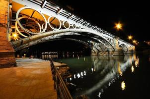 ponte triana sobre o rio guadalquivir ao pôr do sol com reflexos do rio foto