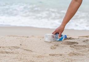 mulher limpa pegando garrafas plásticas na praia. conceito de proteger o meio ambiente, salvar o mundo, reciclar, reduzir o aquecimento global. closeup, fundo desfocado, copie o espaço à esquerda foto