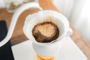 café de gotejamento, derramando uma água quente sobre um café de gotejamento na mesa foto