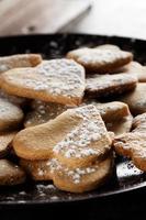 deliciosos biscoitos caseiros em forma de coração polvilhados com açúcar de confeiteiro em pano de saco e tábuas de madeira. imagem vertical vista contra a luz de fundo. foto