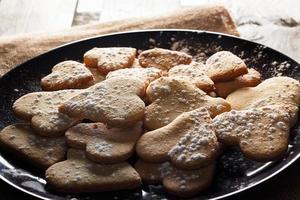 deliciosos biscoitos caseiros em forma de coração polvilhados com açúcar de confeiteiro em pano de saco e tábuas de madeira. imagem horizontal vista contra a luz de fundo. foto