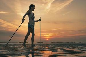 menina praticando caminhada nórdica na praia ao amanhecer foto