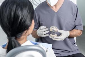 dentista mostrando um molde dental aberto para um paciente em uma clínica odontológica foto