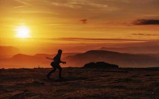 homem feliz de pé em um penhasco ao pôr do sol foto