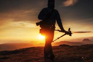 homem feliz de pé em um penhasco ao pôr do sol foto