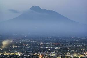 uma vista da cidade e uma grande montanha merapi foto