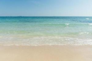 praia e ondas do mar tropical com céu azul no fundo do dia ensolarado. espaço de cópia foto