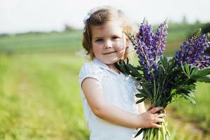 menina com lindas flores azuis em uma noite ensolarada de verão. foto