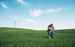 família feliz abraçando em um campo de trigo verde foto