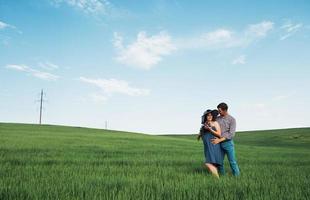 família feliz abraçando em um campo de trigo verde foto