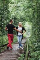casal apaixonado em um túnel de árvores verdes na ferrovia foto