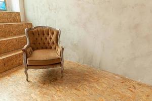lindo quarto interior limpo biege clássico de luxo em estilo grunge com poltrona barroca marrom. cadeira marrom-cinza antiga vintage ao lado da parede. projeto de casa minimalista. foto