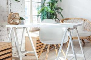 interior de escritório em casa moderno loft elegante. espaçoso apartamento de design com paredes claras, grandes janelas e escrivaninha. decoração moderna limpa com móveis elegantes em estilo escandinavo minimalista. foto