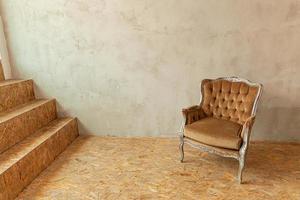 lindo quarto interior limpo biege clássico de luxo em estilo grunge com poltrona barroca marrom. cadeira marrom-cinza antiga vintage ao lado da parede. projeto de casa minimalista. foto