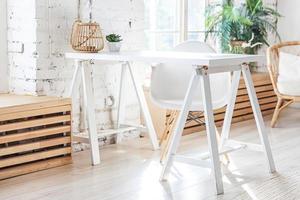 interior de escritório em casa moderno loft elegante. espaçoso apartamento de design com paredes claras, grandes janelas e escrivaninha. decoração moderna limpa com móveis elegantes em estilo escandinavo minimalista. foto