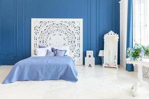 lindo quarto interior limpo clássico de luxo na cor branca e azul profundo com cama king-size e móveis esculpidos chiques. quarto interior elegante moderno brilhante e sala de estar em estilo minimalista. foto