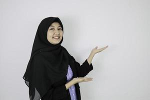 feliz jovem islão asiático usando lenço na cabeça é sorriso e apontando ao lado. foto